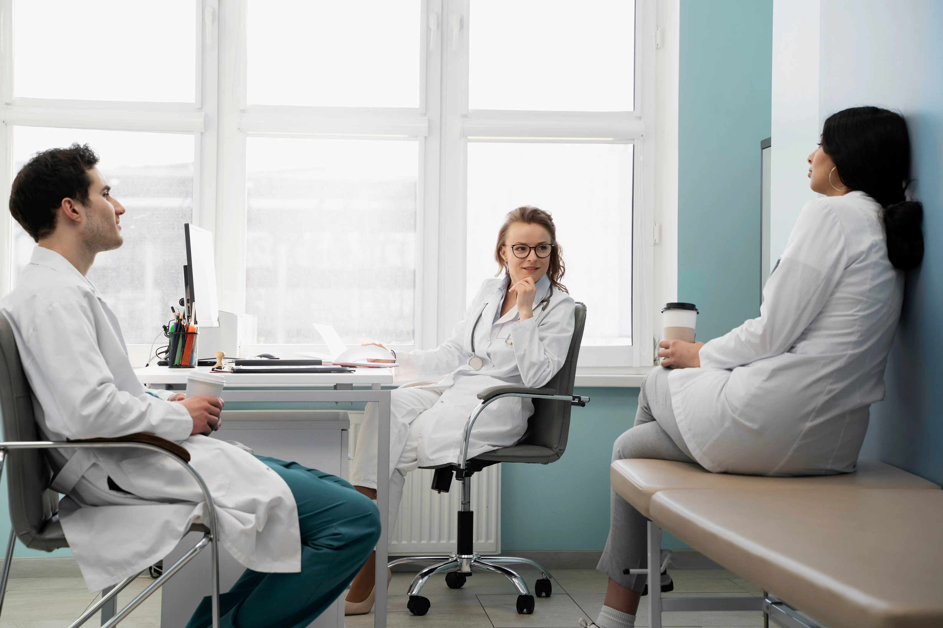 Three clinicians talking together in a bright consulting room.