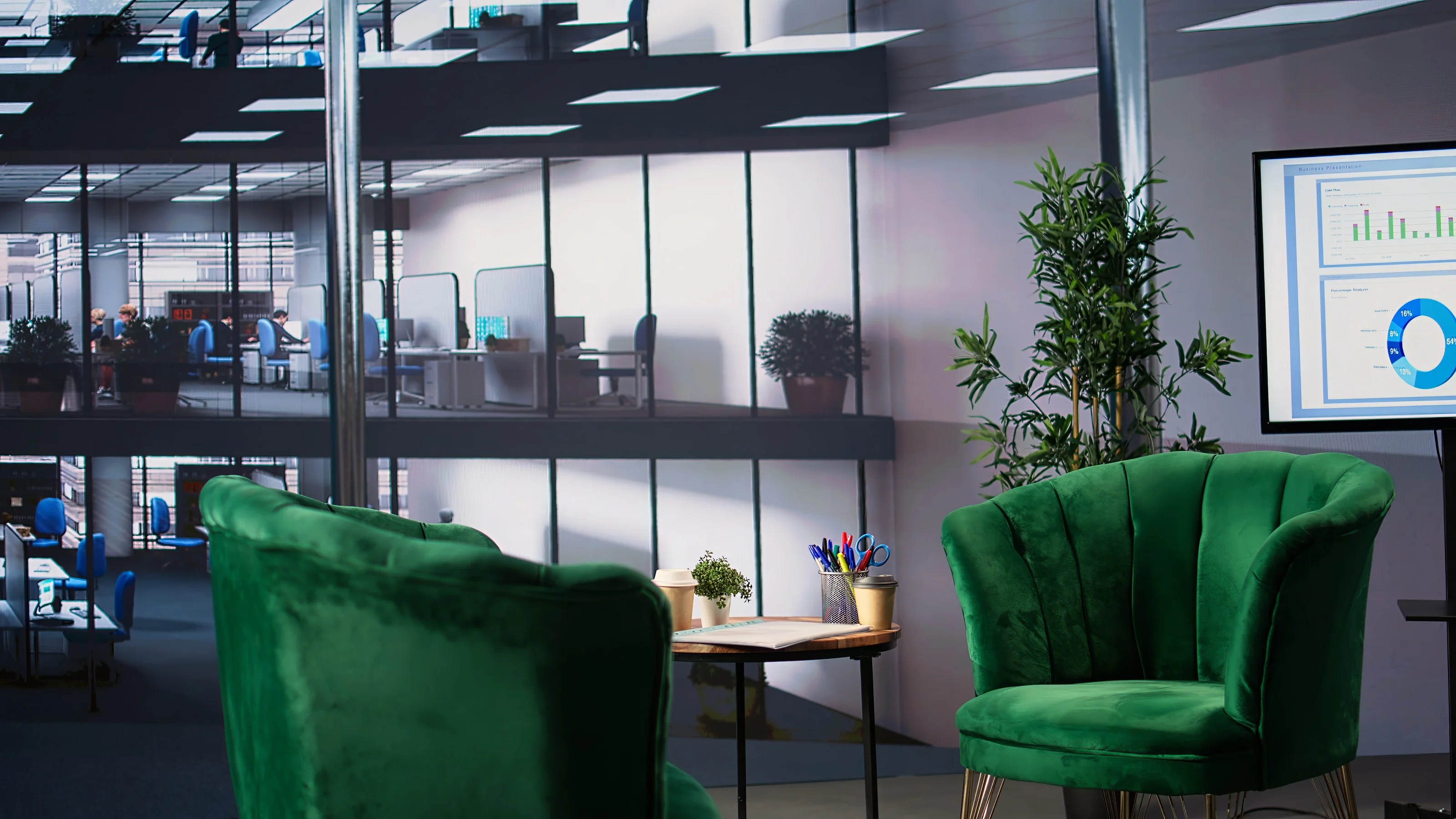 A quiet seating area in a modern office, looking across a glass atrium to the workspaces beyond.