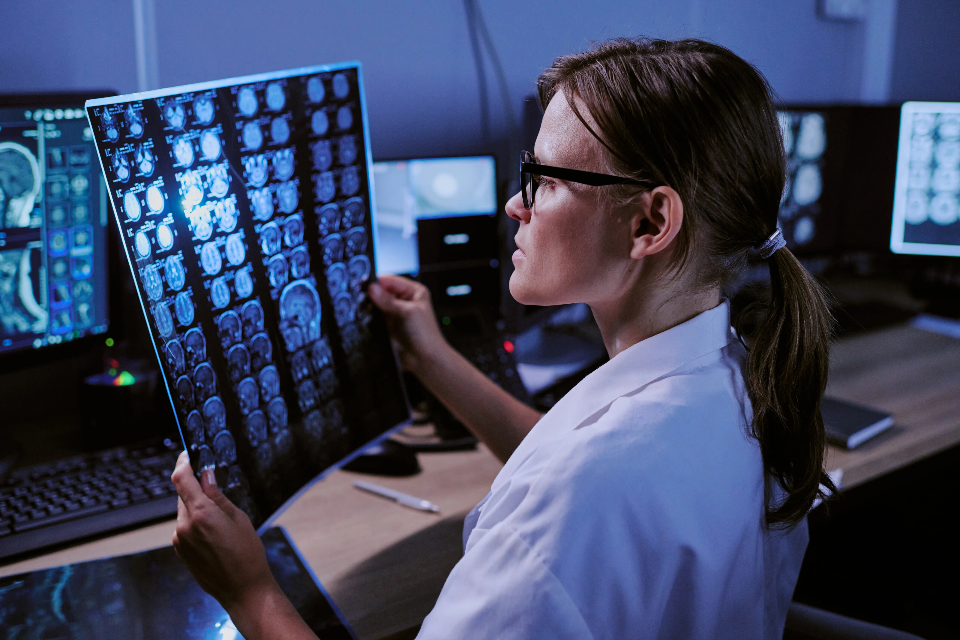 A doctor examining medical scans on a lightbox in a darkened office.